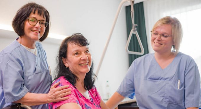 Pflegefachkräfte schieben Patientin im Rollstuhl