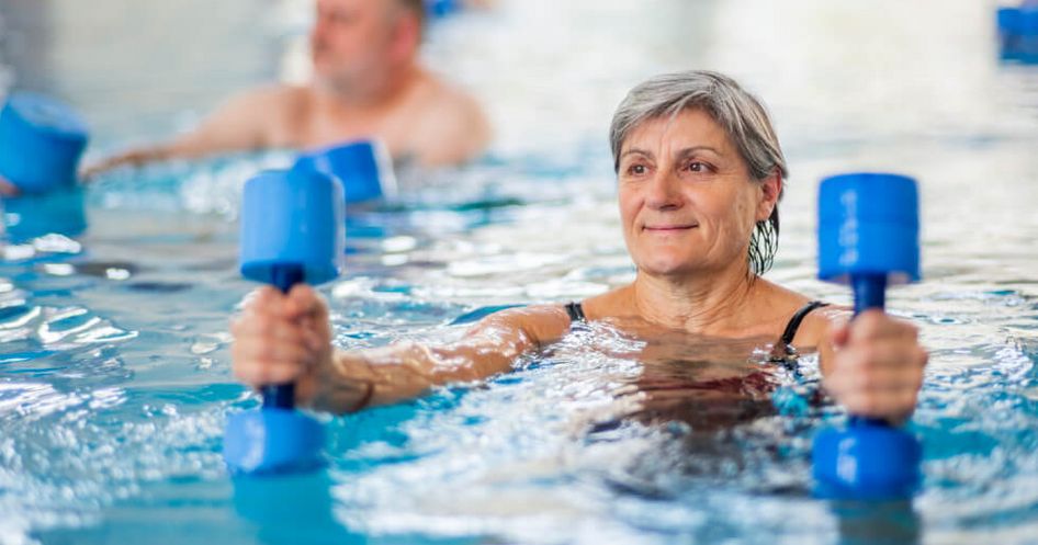 Patienten trainieren im Wasser mit kleinen Hanteln in der Wassergymnastik