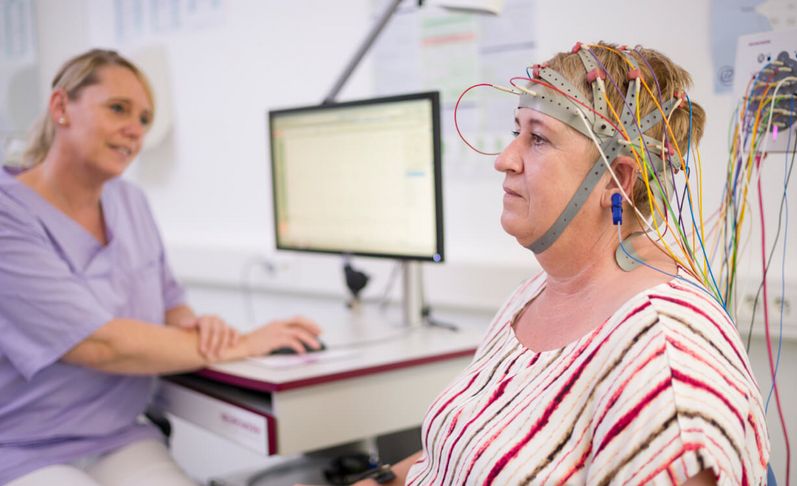 Pflegekraft beobachtet Patientin beim EEG