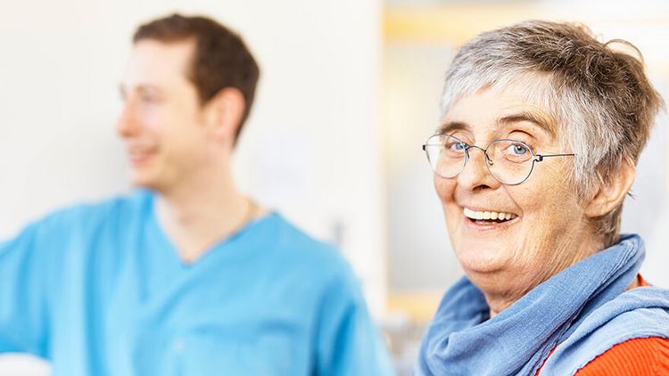 Pflegekraft freut sich mit älterer Patientin