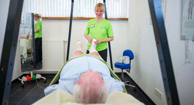 Therapeutin massiert den Fuß eines Patienten