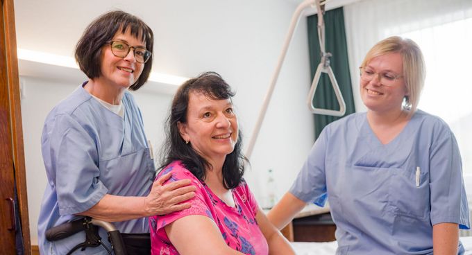 Pflegekräfte sprechen mit Patientin im Rollstuhl