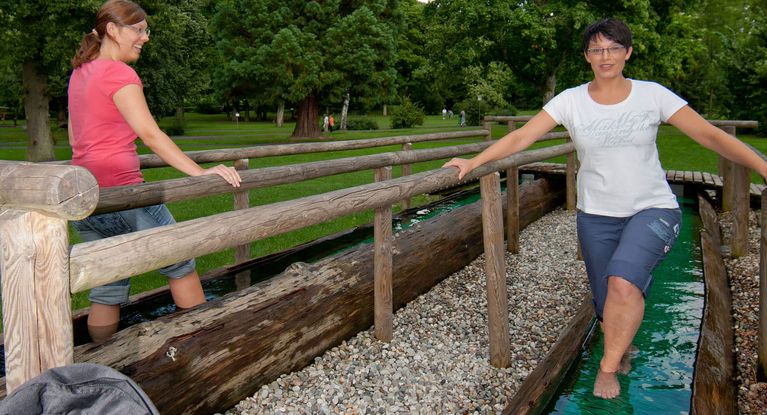 Patienten stapfen in der Kneippanlage im Barfusspfad